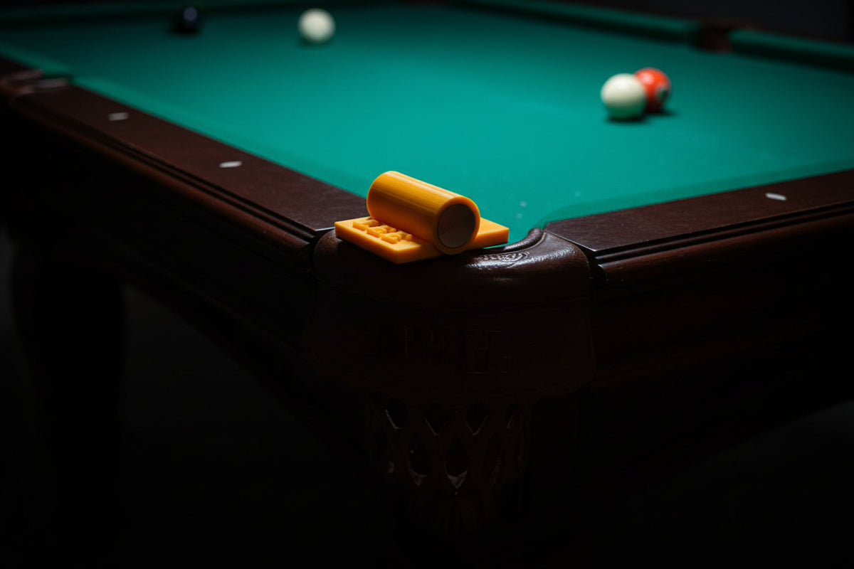 "Rail Mate yellow 3D-printed pool table rail bridge close-up showing cue ferrule opening, LH Inventions branding, and rubber grip base on rail edge"