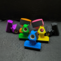 Bridge Mate X2 3D-printed billiard bridge heads in blue, green, yellow, orange, pink, and purple — multi-color cue bridge head collection displayed on dark surface showing BridgeMate X2 branding"